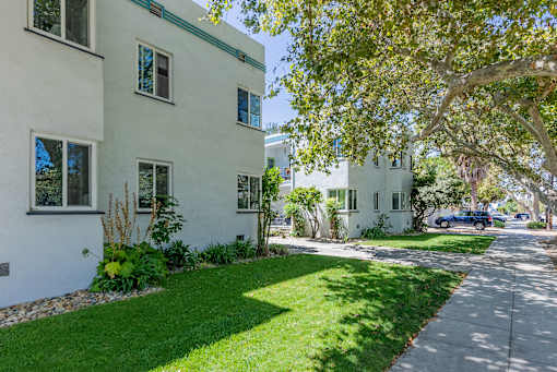 the exterior of a white house with a sidewalk and grass