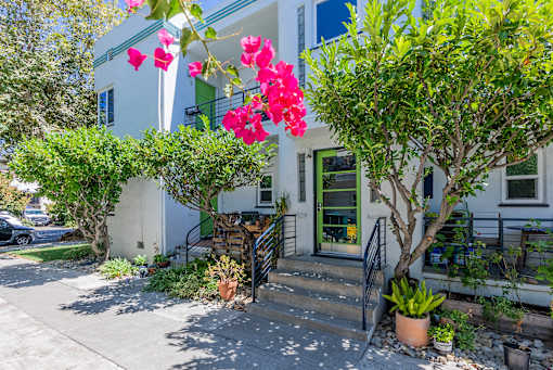 a blue and white house with pink flowers in front of it