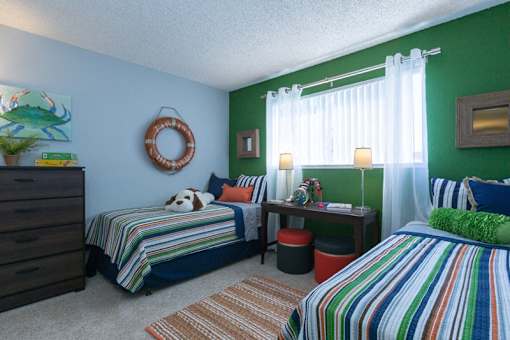A bedroom with two beds, one with a green pillow and striped bedspread.