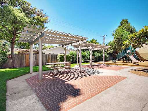 A park with a bench and a pergola.