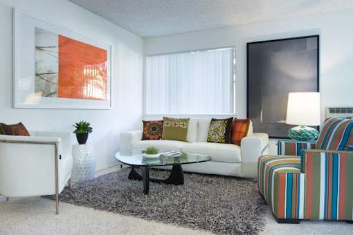 A living room with a white couch, a coffee table, and a striped armchair.