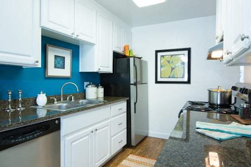 A kitchen with white cabinets and a black refrigerator.