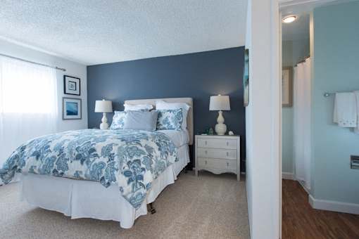 A bedroom with a bed, nightstand, and lamp.