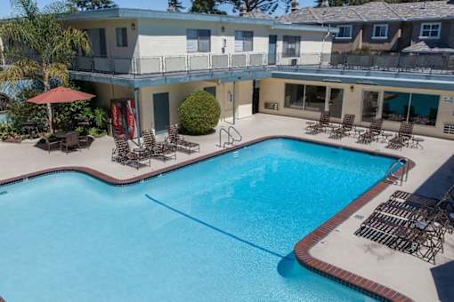 A large swimming pool with a blue line in the middle and chairs around it.