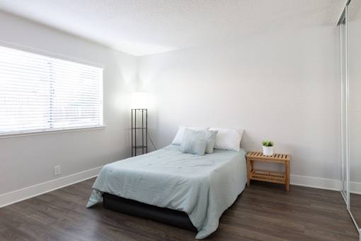 A bedroom with a bed, nightstand, and window.