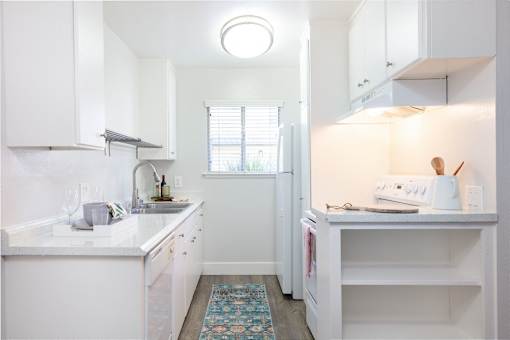 A small white kitchen with a sink and a refrigerator.