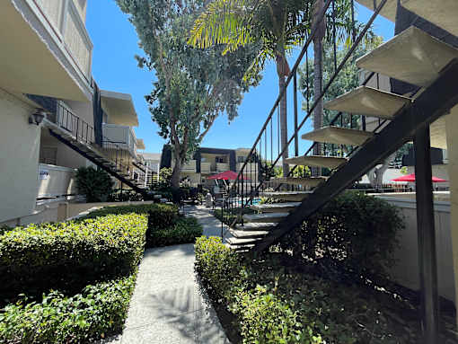 A pathway leads to a building with a black metal staircase.