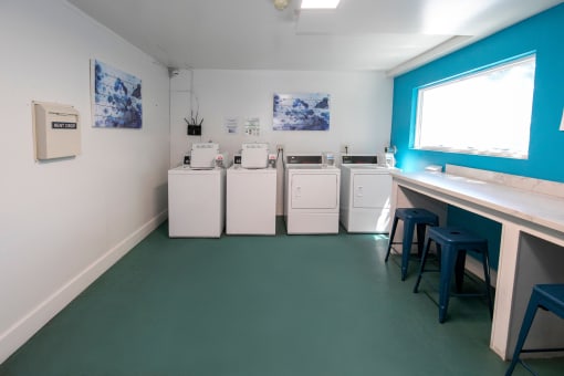 a laundry room with washing machines and a counter with stools