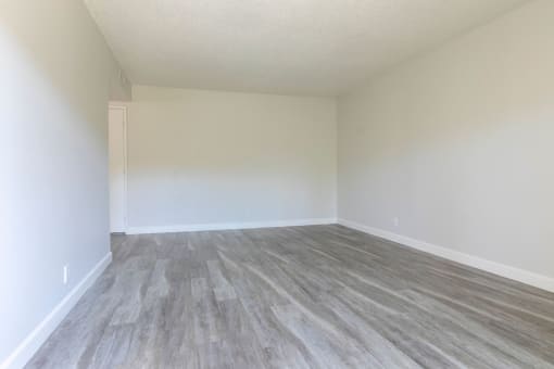 an empty room with vinyl flooring and white walls