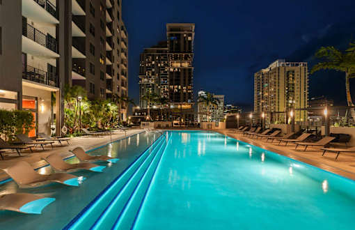 A long rectangular pool with lounge chairs on the side.