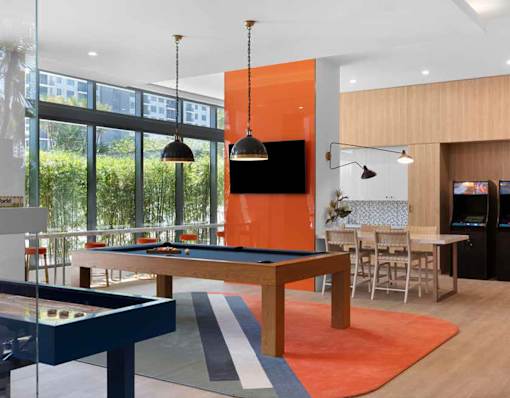 A billiard table is in the middle of a room with a television and a bar.