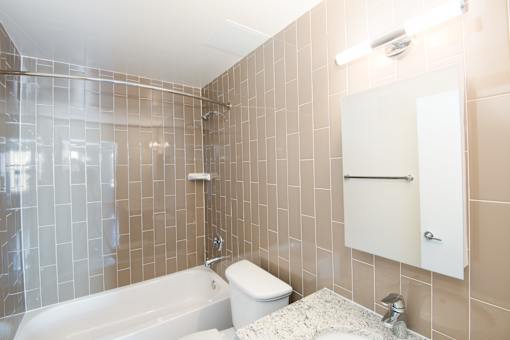 A white bathtub sits in a bathroom with beige tiles.