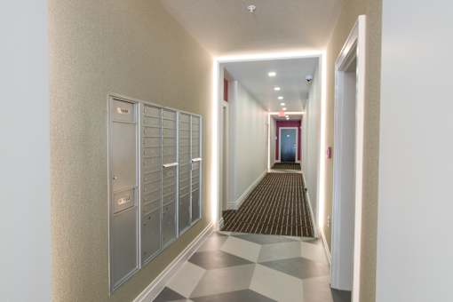 A long hallway with a row of lockers on the left and a checkered floor.
