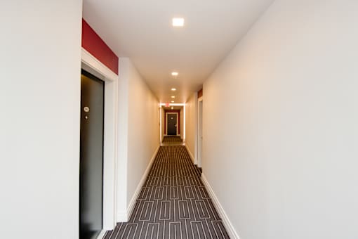 A long hallway with a carpeted floor and white walls.