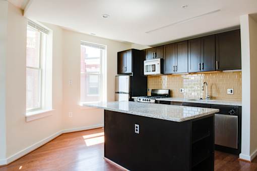 A kitchen with black cabinets and a granite countertop.