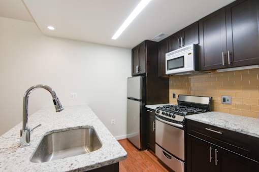A kitchen with a sink, stove, and refrigerator.
