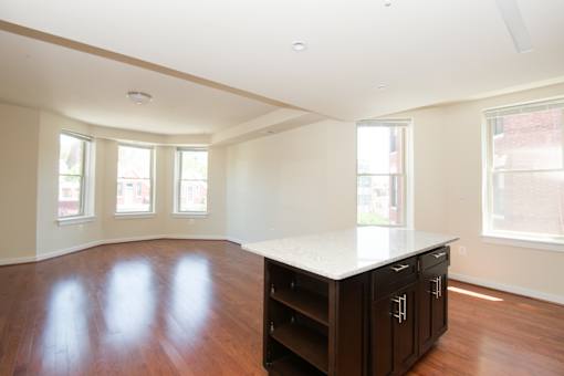 A kitchen with a white counter top and wooden floors.
