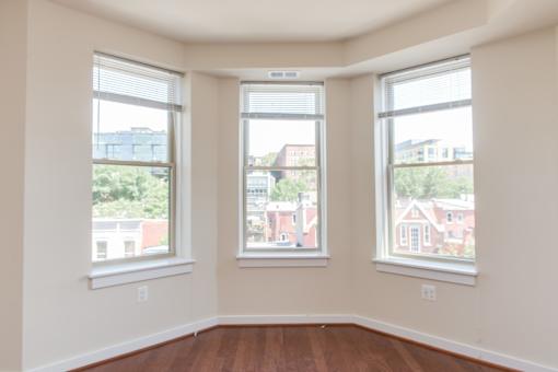 Three windows in a room with white walls and wood floors.