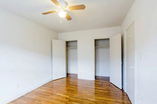 A room with a ceiling fan and wooden floors.