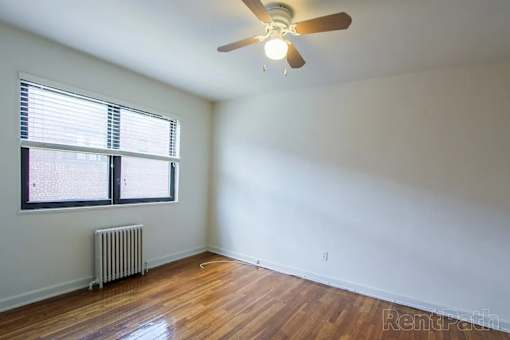 A room with a ceiling fan and a window with blinds.