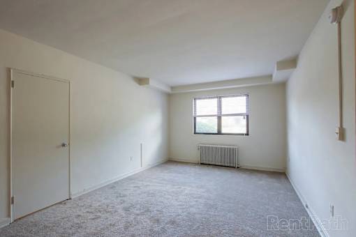 A room with a window and a radiator on the floor.