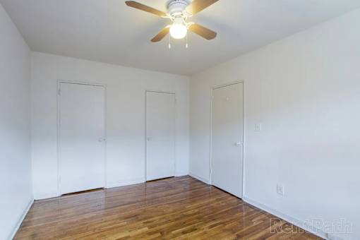 A room with a ceiling fan and three doors.