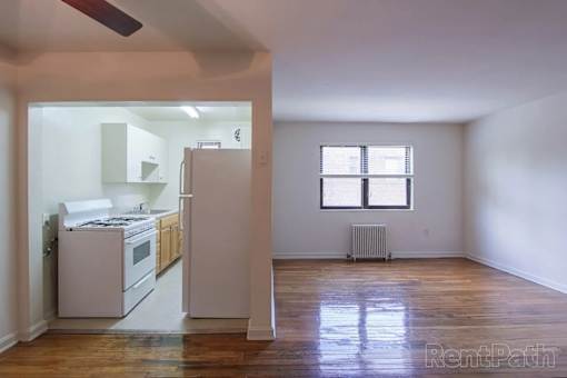 A kitchen with white appliances and wooden floors.