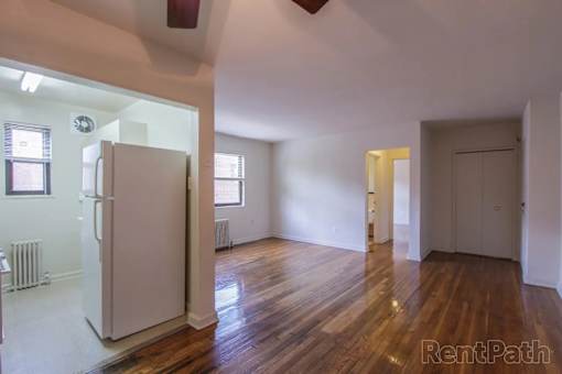 A white refrigerator is in a room with wood floors and white walls.