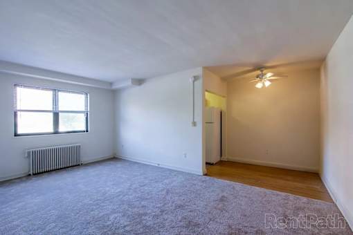 A spacious room with a window and a ceiling fan.