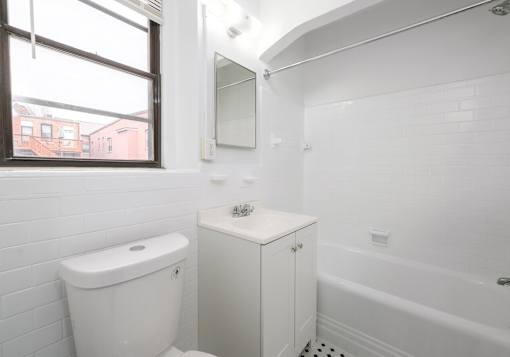 A white toilet sits next to a white sink in a small bathroom.