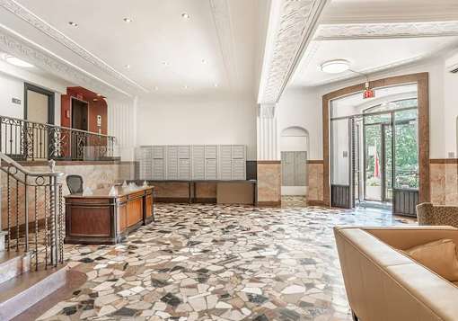 A large, open lobby with a marble floor and a staircase with a metal railing.