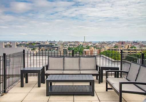 A patio with black furniture overlooking a city.