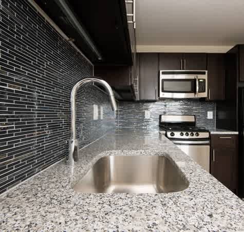 A modern kitchen with a stainless steel sink and a brick wall.