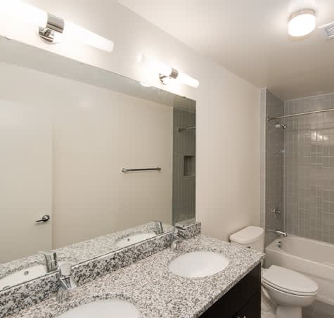 A bathroom with a granite countertop and a white toilet.