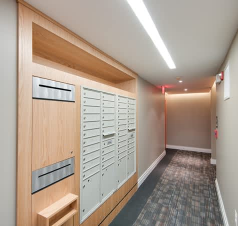 A hallway with a row of lockers on the left and a bench under the first locker.