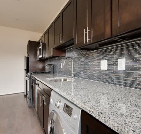A modern kitchen with dark wood cabinets and a granite countertop.