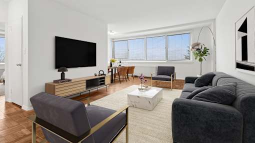 A living room with a grey couch, a wooden entertainment center, and a flat screen TV.