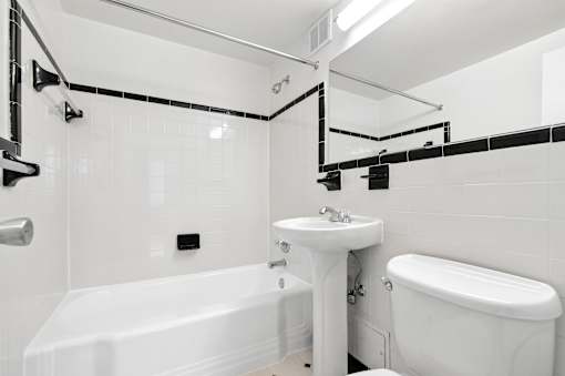 A white bathroom with a tub, sink, and toilet.