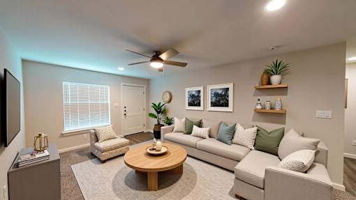 A living room with a white couch, a wooden coffee table, and a flat screen TV.