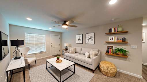 A living room with a white couch, a glass coffee table, and a ceiling fan.