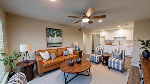 A living room with a brown couch, a coffee table, and a ceiling fan.