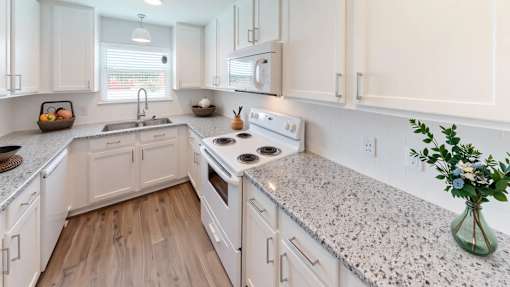 A kitchen with white cabinets and granite countertops.