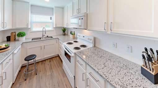 A kitchen with white cabinets and a granite countertop.