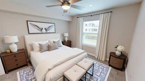 A bedroom with a large bed, a ceiling fan, and a picture of two birds on the wall.