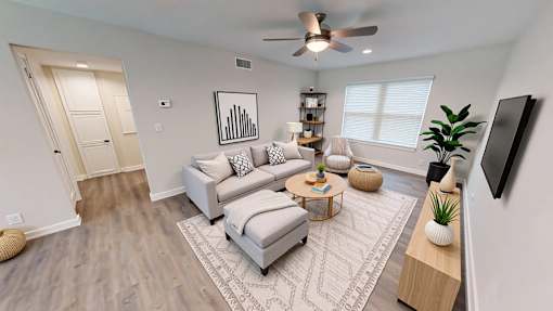 A living room with a grey couch and a white ceiling fan.