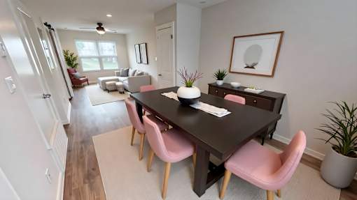 A dining room with a black table and pink chairs.