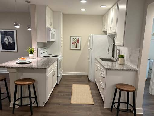 A kitchen with white cabinets and a granite countertop.