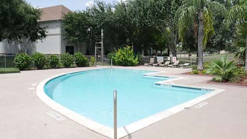 A small pool surrounded by trees and a fence.