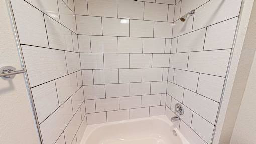 A white tiled shower with a white tub and a white door.