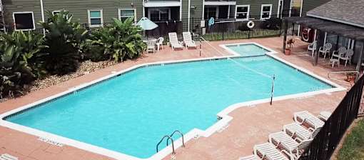 A small pool surrounded by chairs and plants.